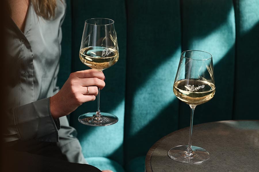 Two glasses of white wine in a green velvet Olivine booth