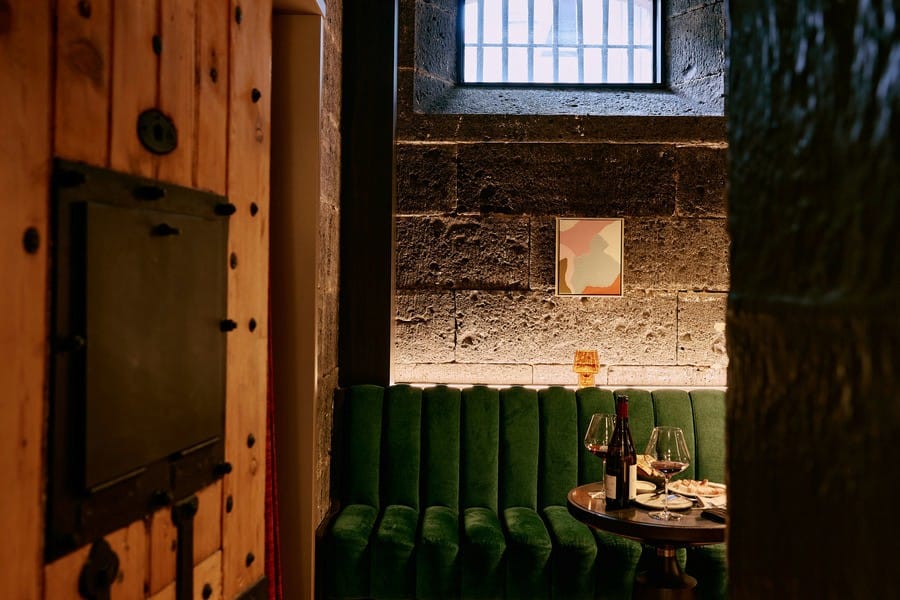 A subtly lit green booth beside the heritage bluestone wall at Olivine