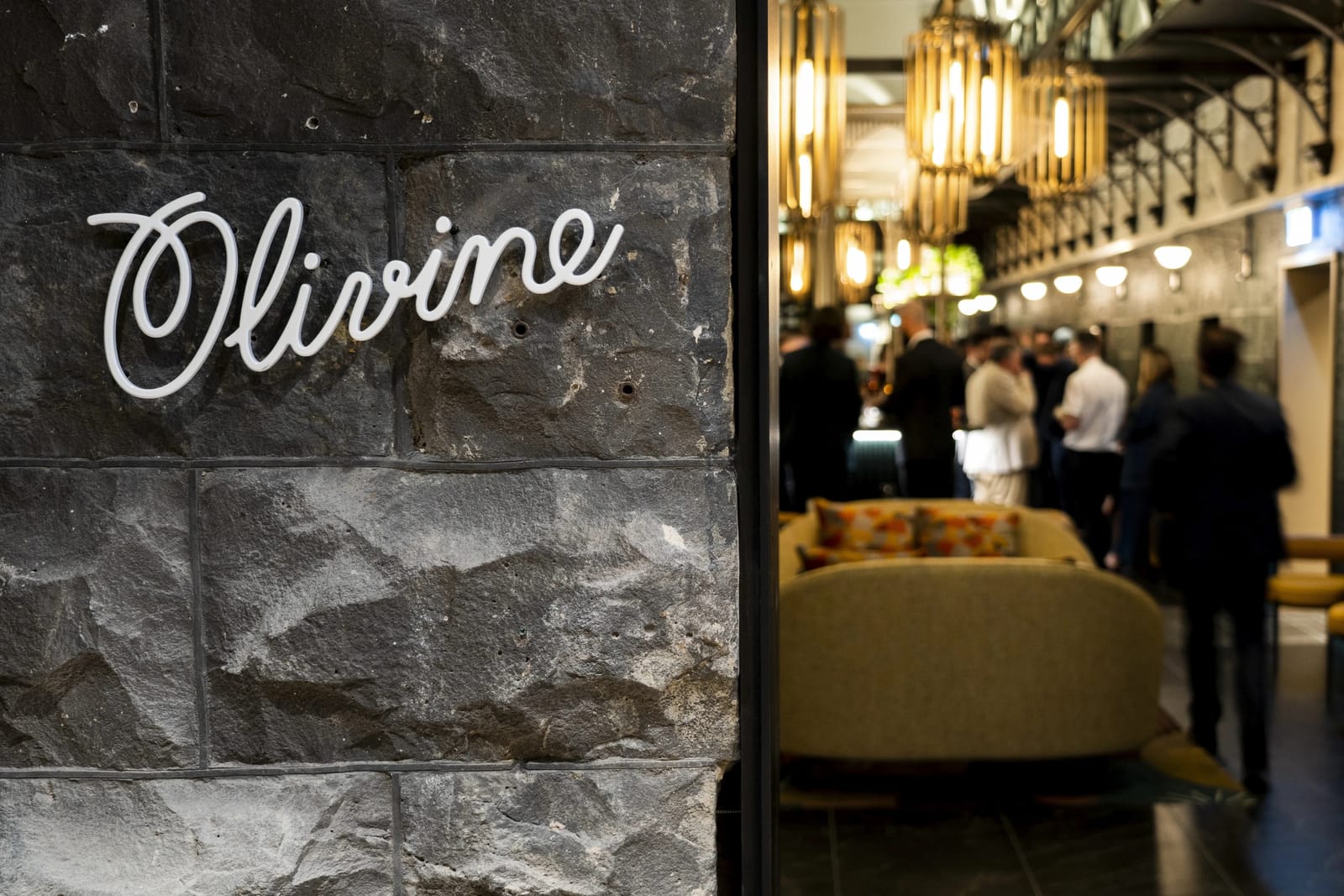 The Olivine neon sign on the heritage bluestone wall
